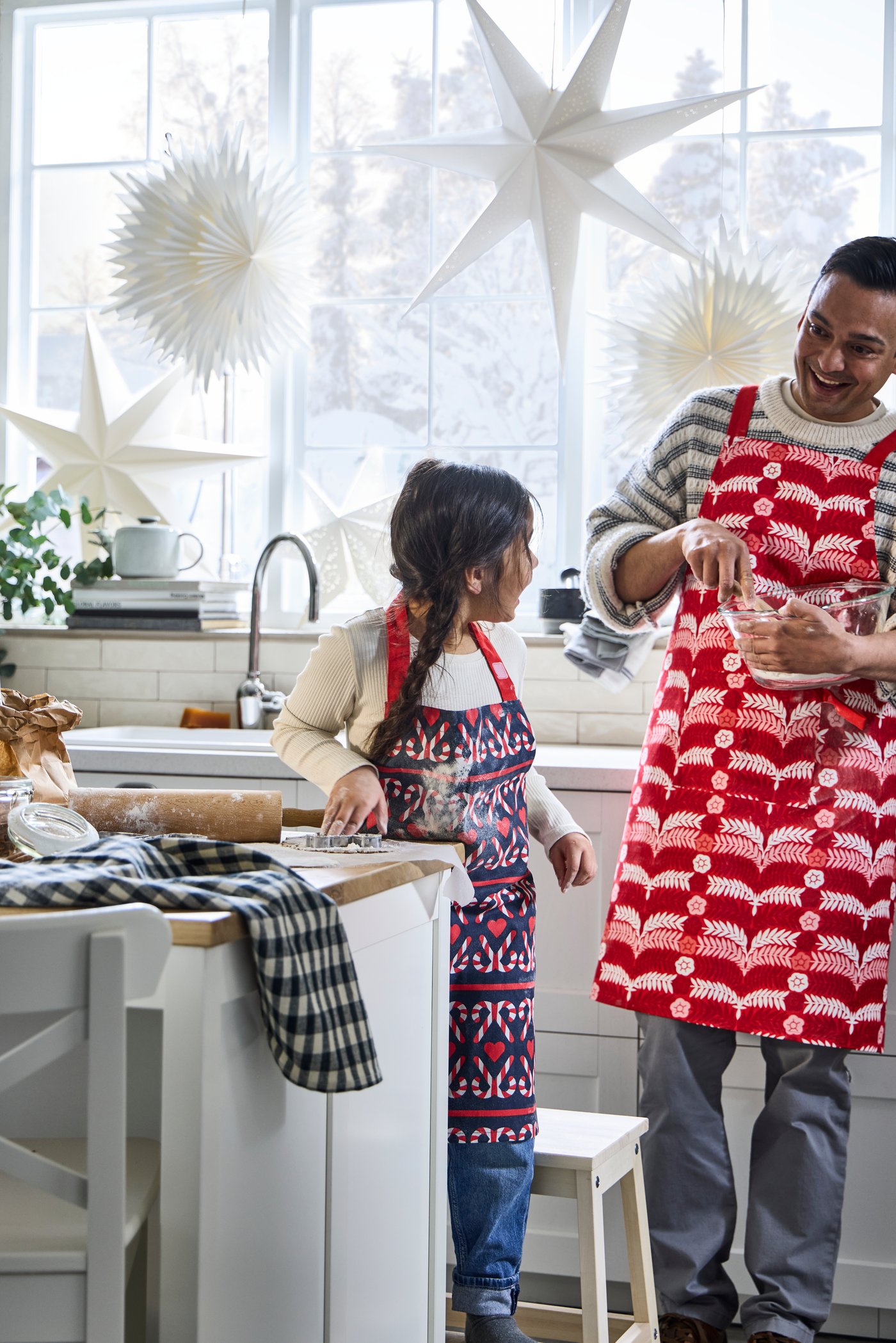 Papà e bambina preparano insieme i biscotti di Natale con utensili IKEA in una cucina decorata a festa.