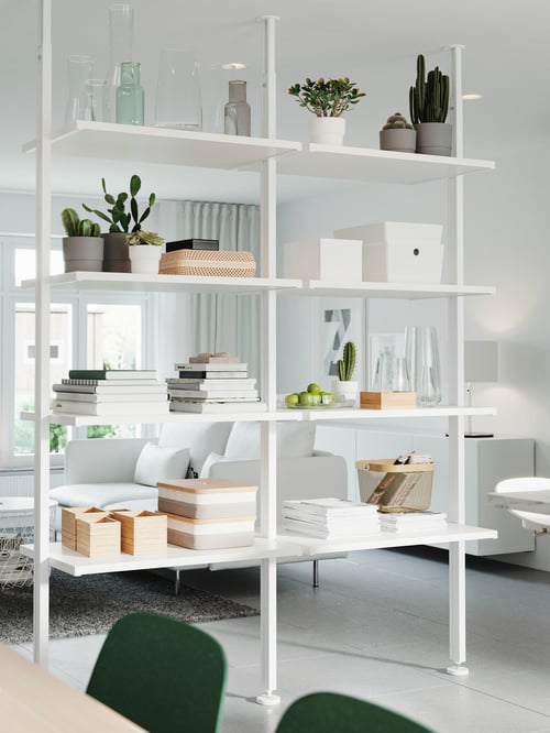 Salon avec un rangement ouvert blanc avec des boîtes rectangulaires avec couvercle, des plantes en pot, des vases et un panier.