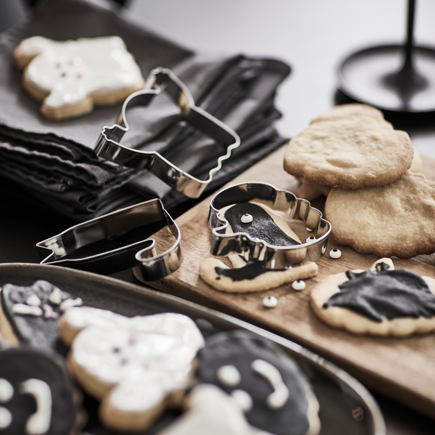 ブラックのテーブルに、さまざまなKUSTFYR/クストフィール クッキー型と、ハロウィンをテーマにデコレーションしたクッキーが置いてある。