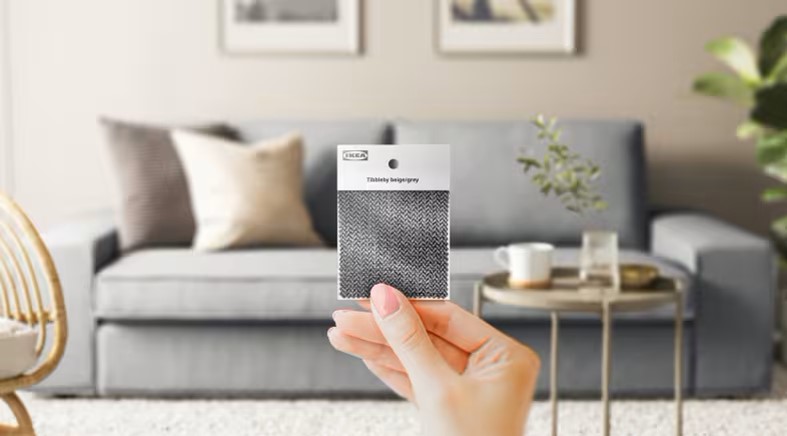 Szürke KIVIK két üléses kanapé, előtte tartott textil mintával.