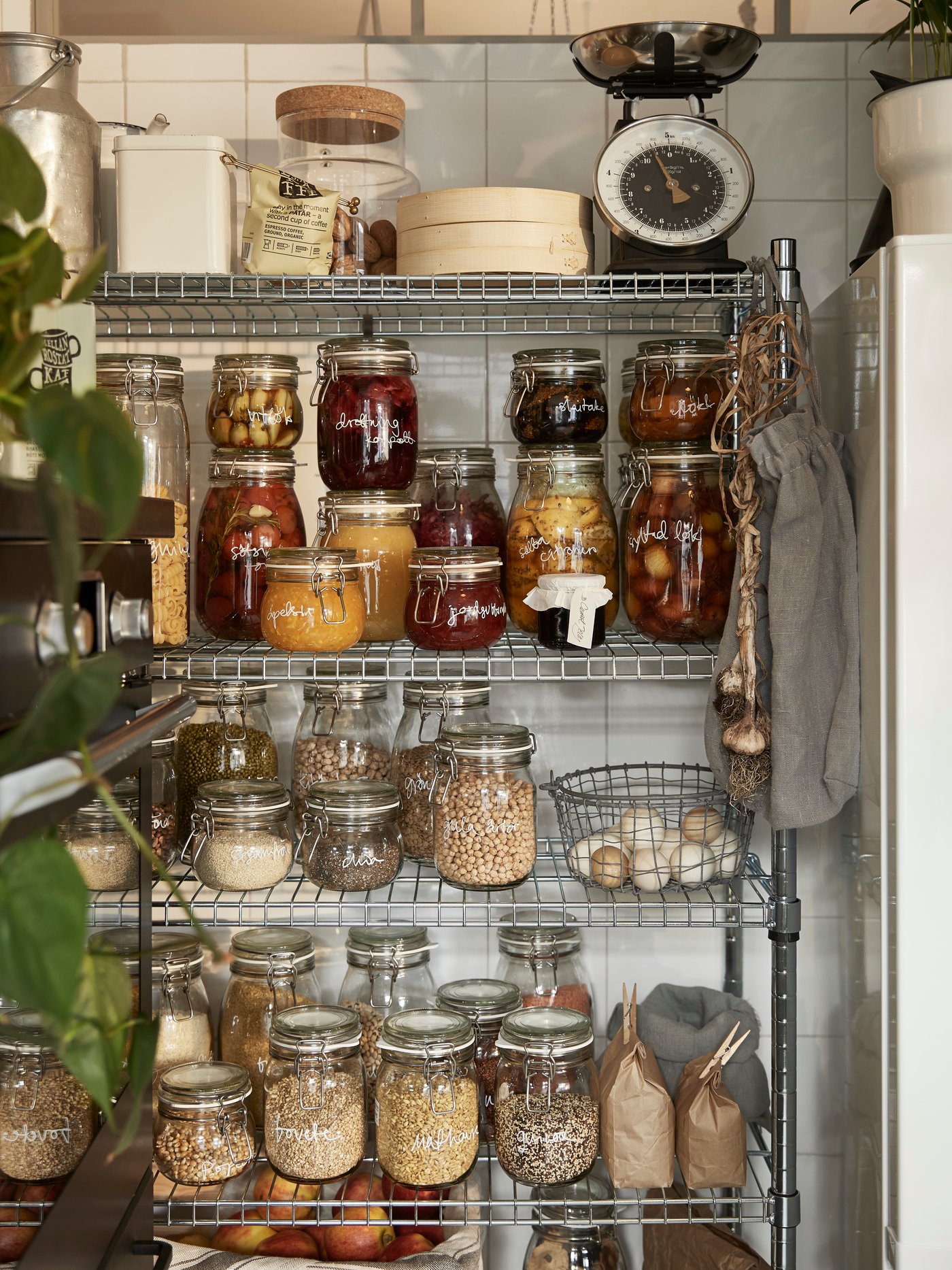 Un mueble de despensa IKEA con muchos frascos con granos y alimentos no perecibles en el interior.