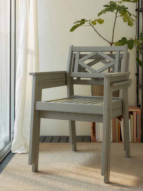 Deux chaises à accoudoirs grises empilées sur un tapis beige. Étagère grise et plante en arrière-plan.
