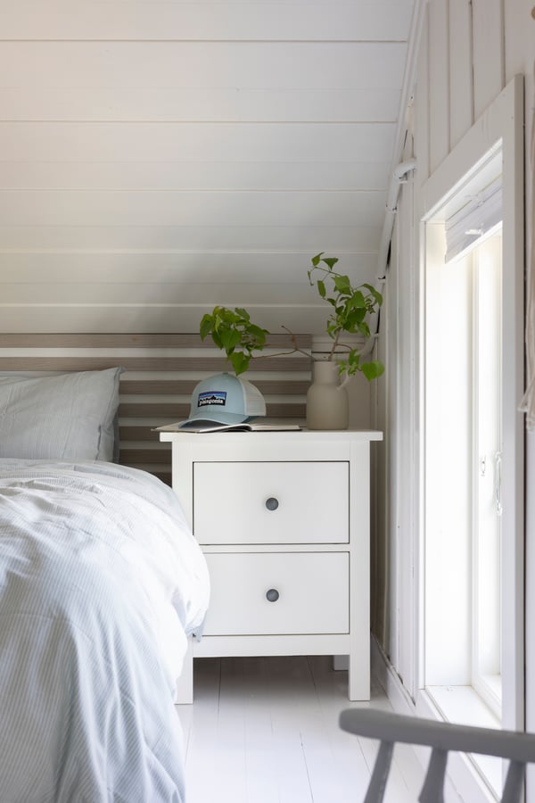Lähikuva valkoisesta HEMNES-yöpöydästä sängyn vieressä.