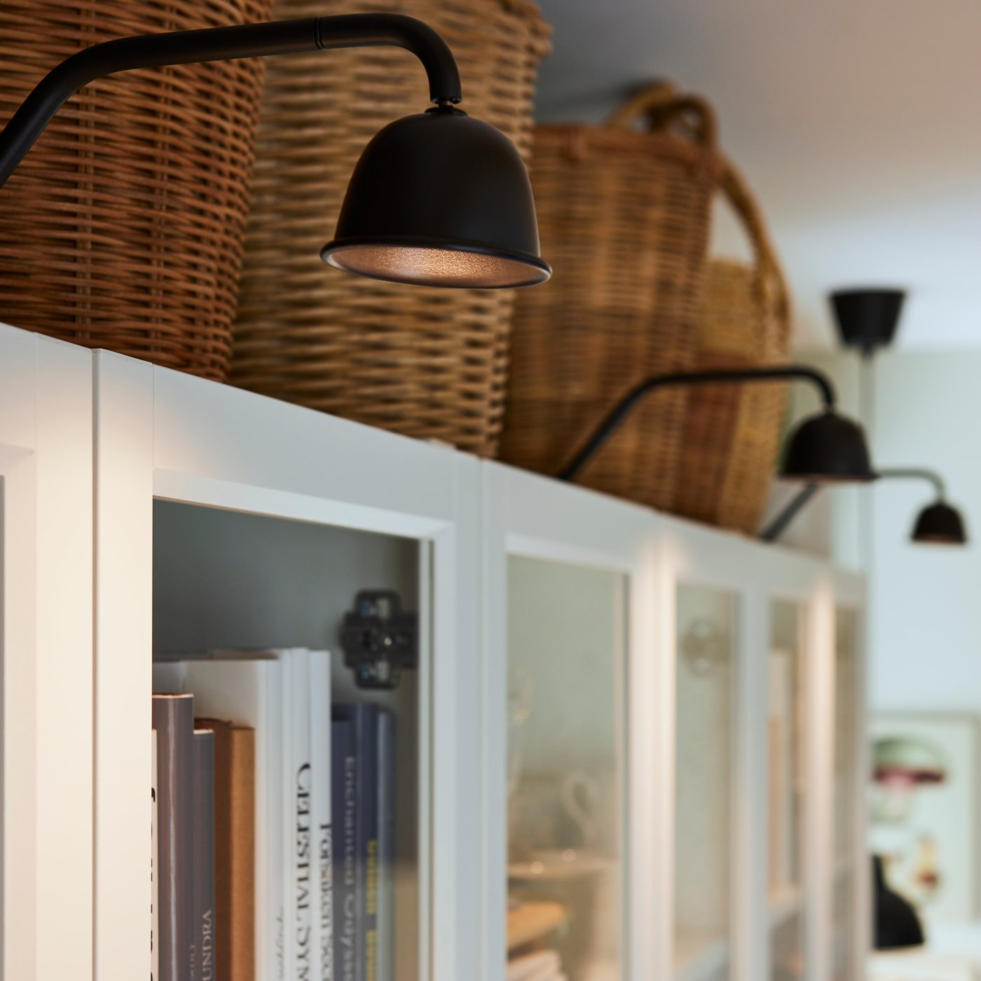 Närbild av TVÄRDRAG belysning som är integrerad i en vit bokhylla med glasdörrar.