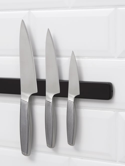 Nahaufnahme der IKEA 365+ Messer im 3er-Set, die an einer Magnetleiste an einer weiß gefliesten Wand hängen.