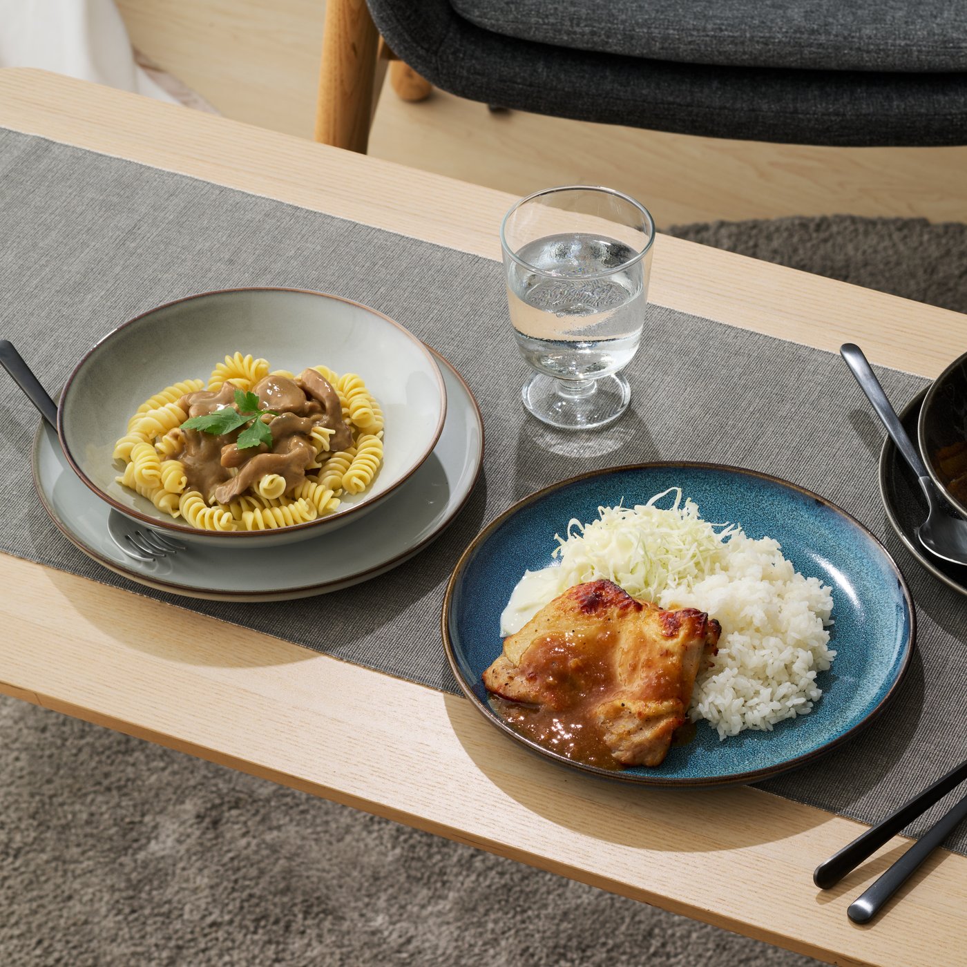 木目のテーブルに置かれた3つの器に、ライス料理やパスタ風の料理が盛り付けられている。