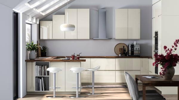 High-gloss light beige modern kitchen with a black worktop in a grey room with light wood flooring