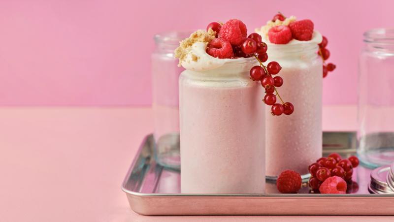 To svagt pink LÅNGLUR frugtsmoothie-milkshakes fyldt med røde hindbær, ribs og cookie crumble.