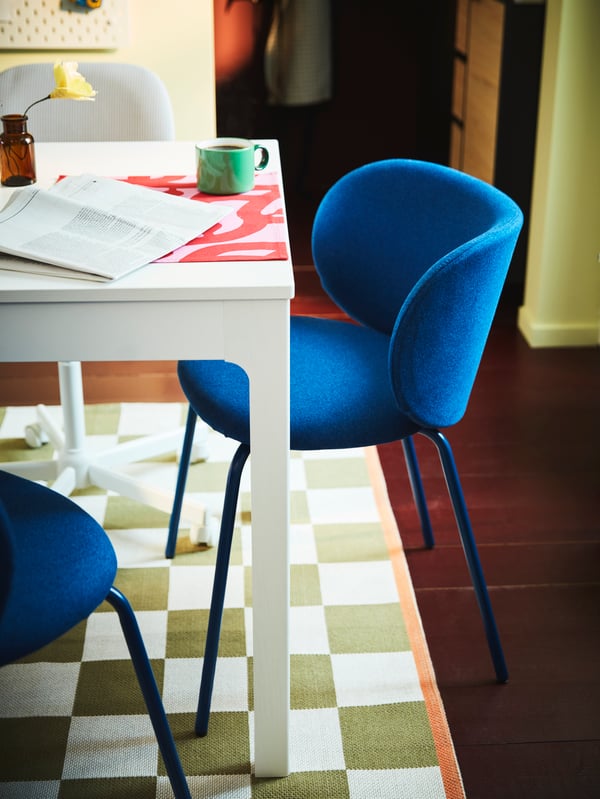 Blue KRYLBO chairs around a white EKEDALEN extendable table placed on a KLASSRUM rug. A PIGGÅL mug is placed on the table.