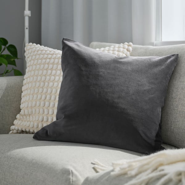 Två prydnadskuddar i beige och grått i ljusgrå soffa.