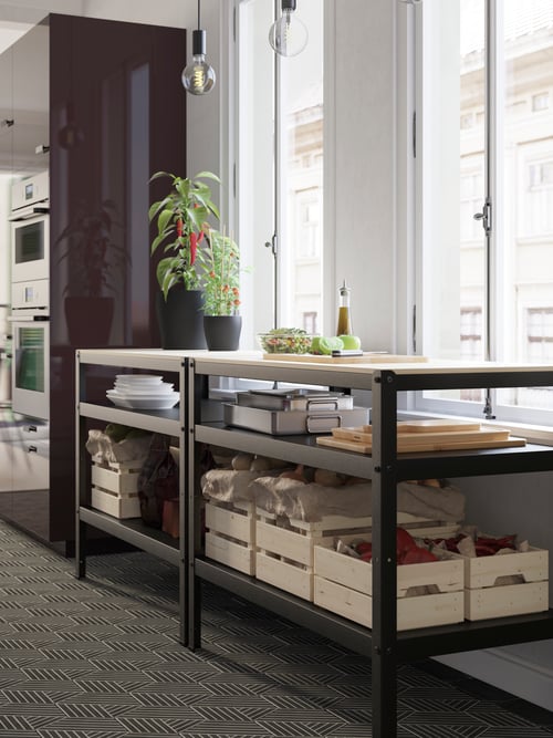 Two black/pine plywood BROR work benches by a window. A salad is being prepped on top with produce kept on the shelves below.