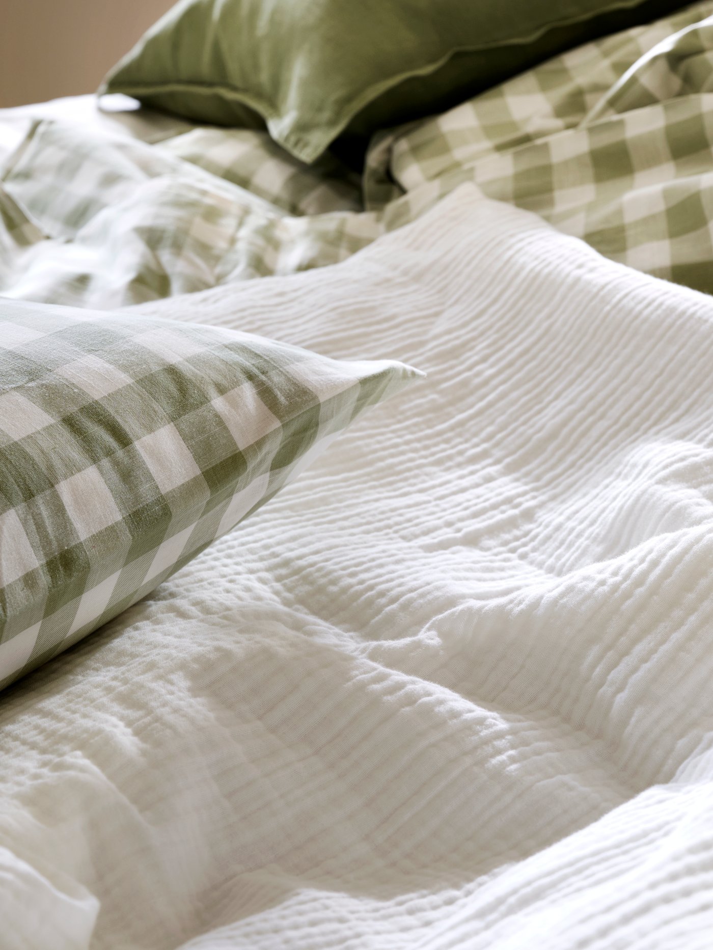 Gros plan sur des housses de couette et taies d’oreiller SCHERSMIN et EKTANDVINGE en vert clair et blanc.