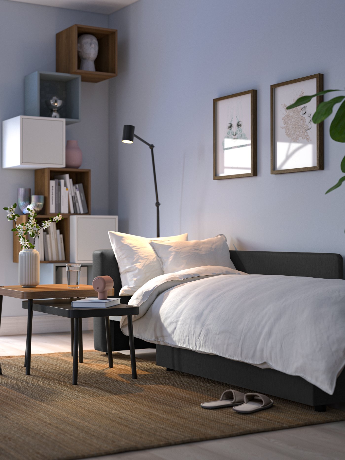 Ein dunkelgraues SKÖNABÄCK 2-Sitzer-Schlafsofa, das mit einer Bettdecke und Pölstern bereits für die Nachtruhe vorbereitet ist.