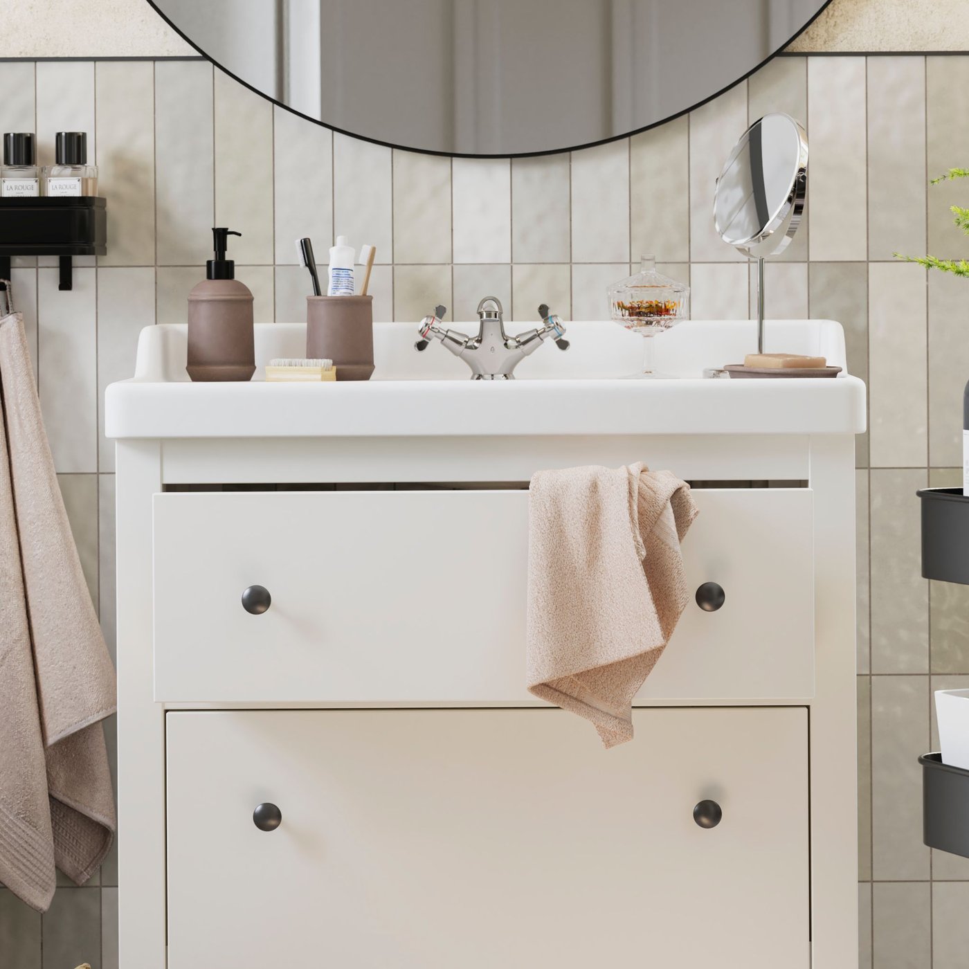 Biała szafka łazienkowa HEMNES z dwiema szufladami stoi pod okrągłym lustrem.