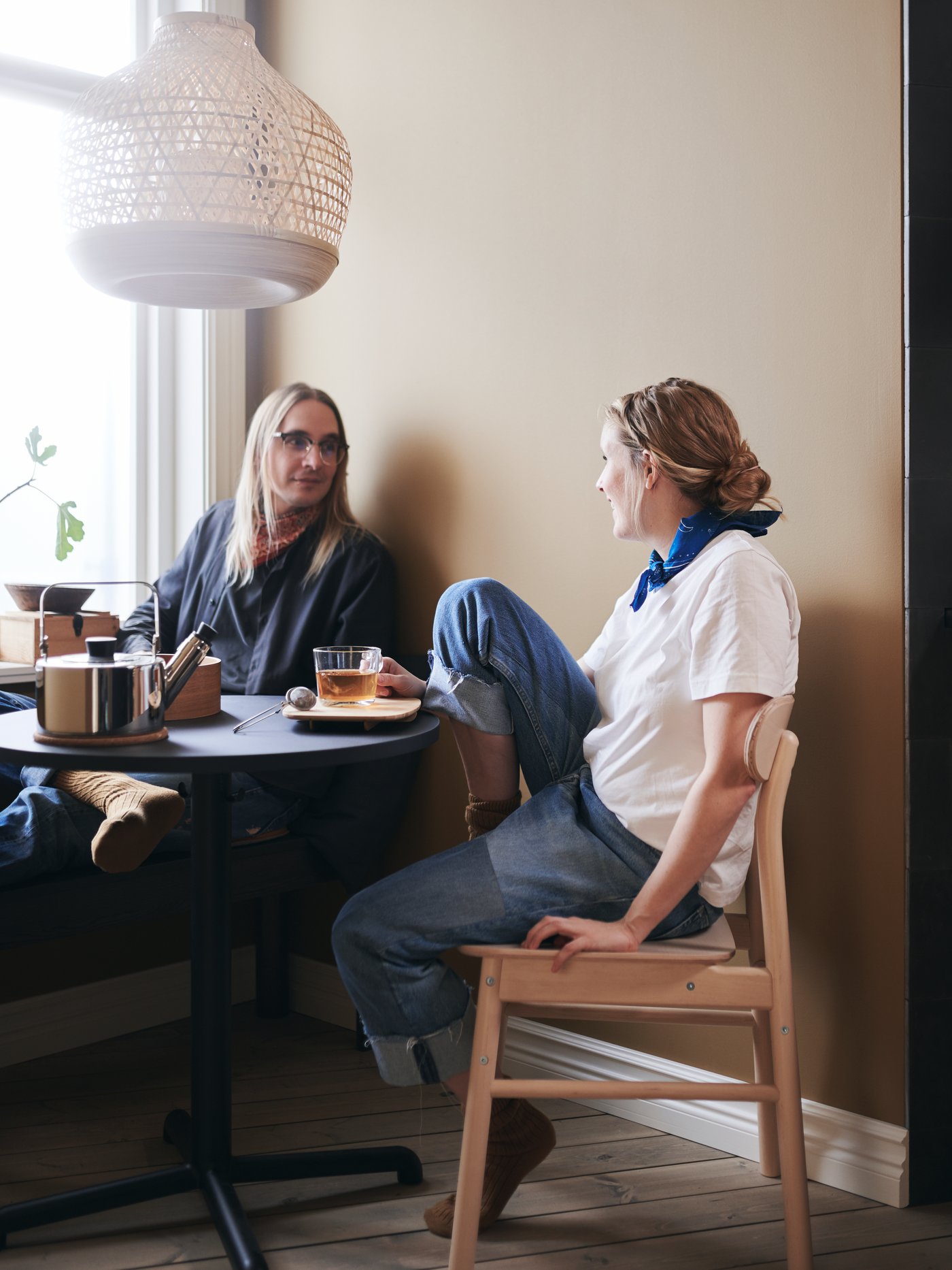 A couple enjoy a quiet tea break at their STENSELE table, with a MISTERHULT pendant lamp hanging overhead.