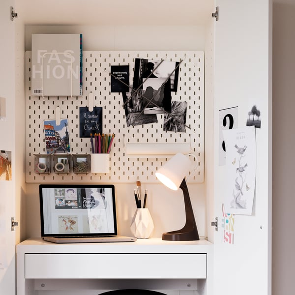 Espacio de estudio con escritorio de color blanco, con un organizador de pared  una lampara de escritorio de color negro con blanco.
