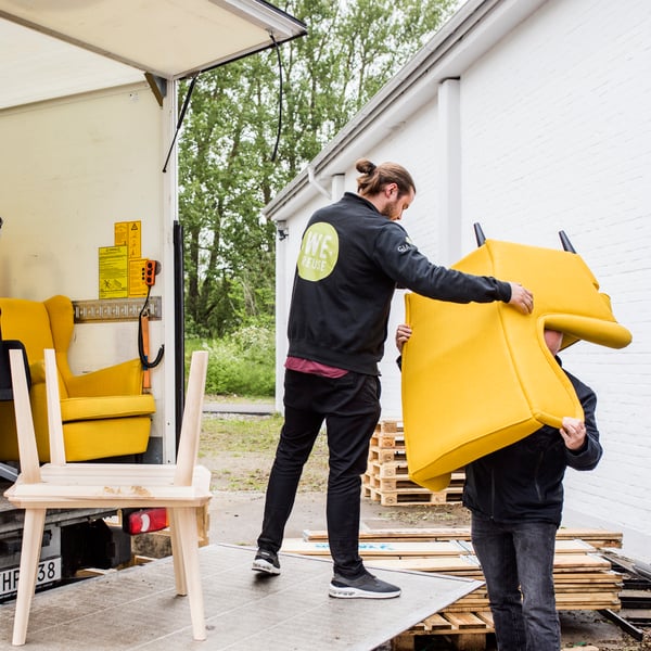 En ældre gul STRANDMON lænestol bliver løftet ud i en lastbil.