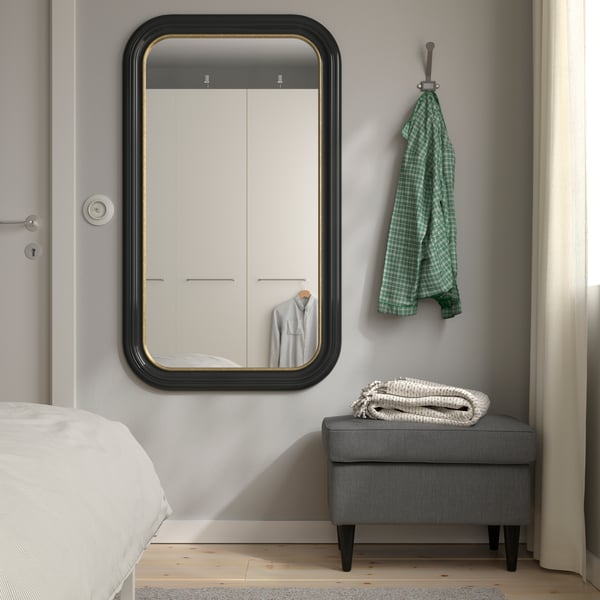 Un miroir ALMARÖD en noir accroché au mur d’une chambre. 