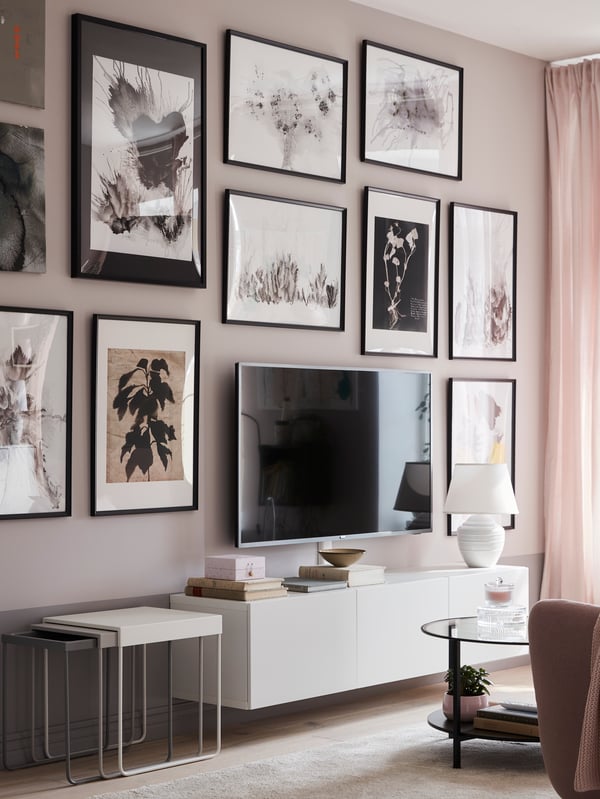 Un soggiorno con un mobile bianco BESTÅ con ante. Accanto, tre tavolini e di fronte un tavolino VITTSJÖ. Sulla parete, una tv e cornici con stampe e foto KNOPPÄNG.