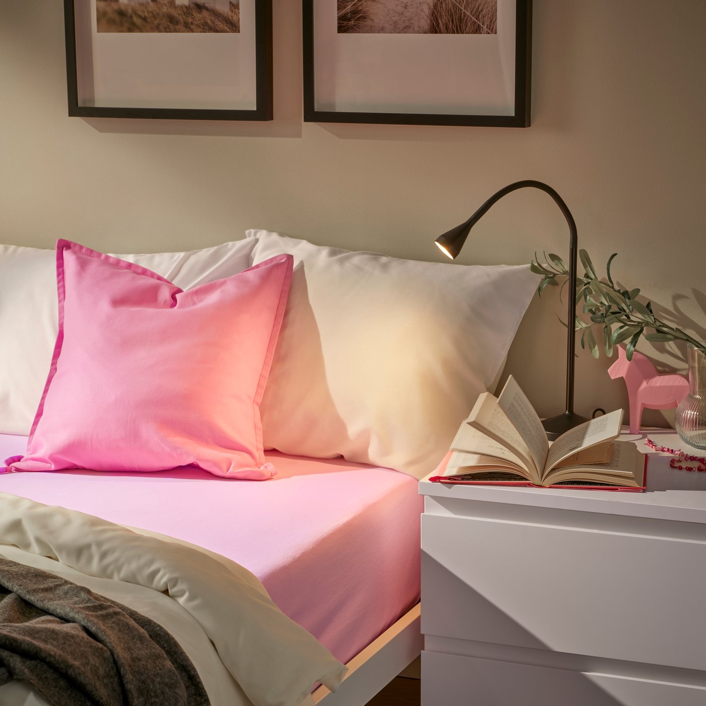 Ein weißes MALM Bett ist mit einem rosa VÅRVIAL Spannbettlaken und einer weißen PILTANDVINGE Bettwäsche bezogen. Passend dazu liegt ein rosa GURLI Kissen aus 100% Baumwolle auf dem Bett.