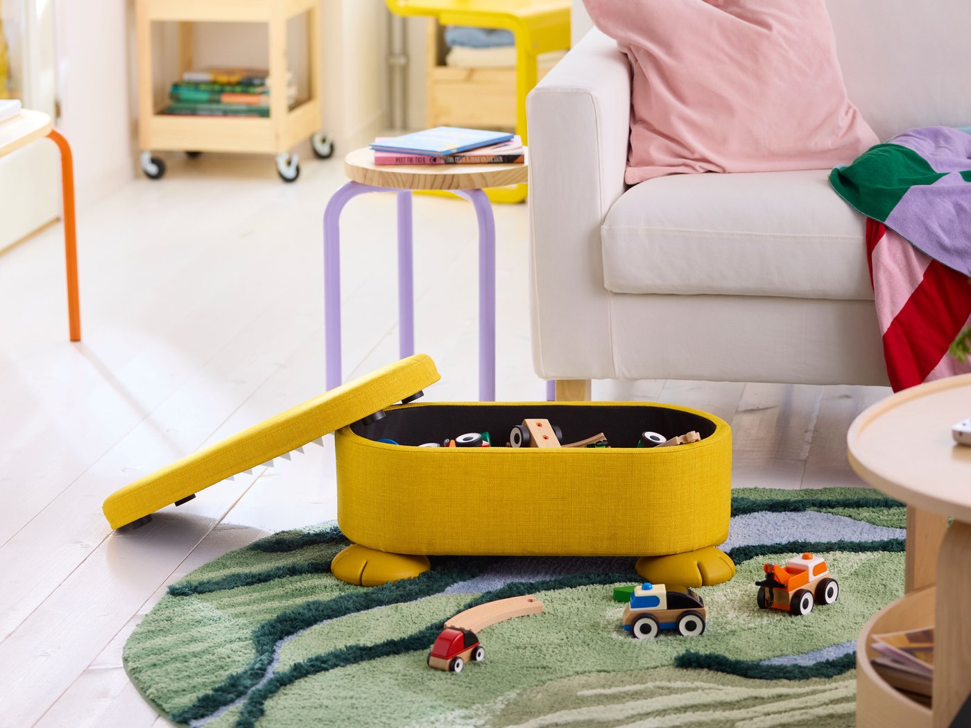 Ein gelber GREJSIMOJS-Sitzhocker mit Stauraum in einem Wohnzimmer