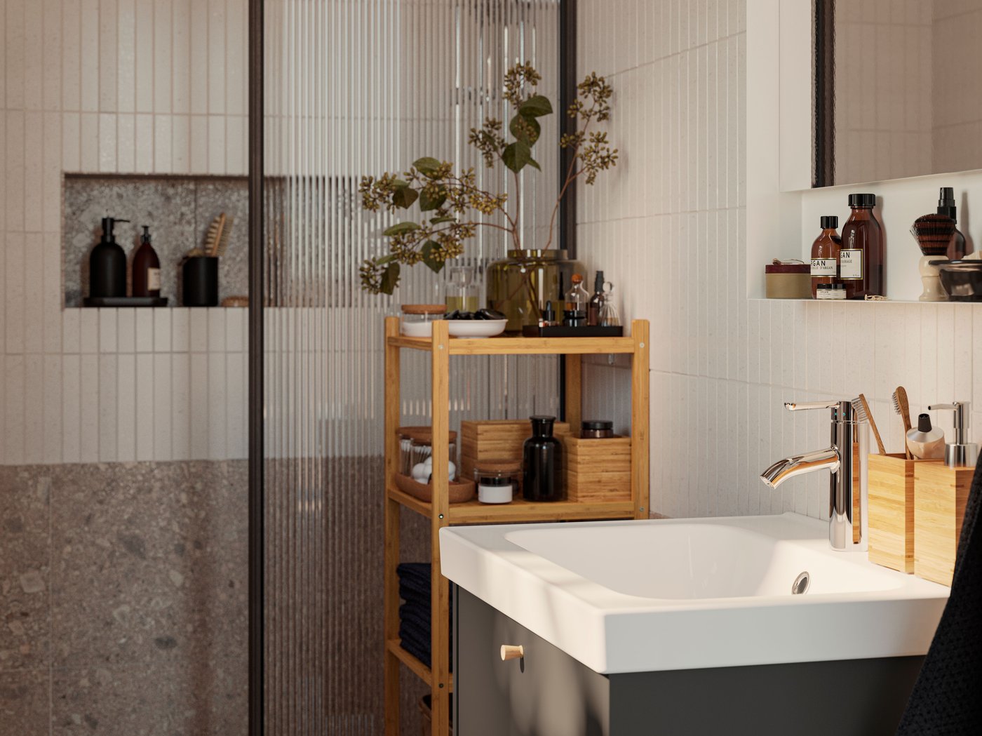 A HAVBÄCK wash-stand in dark grey with a white ORRSJÖN washbasin is standing next to a RÅGRUND shelf made of bamboo.