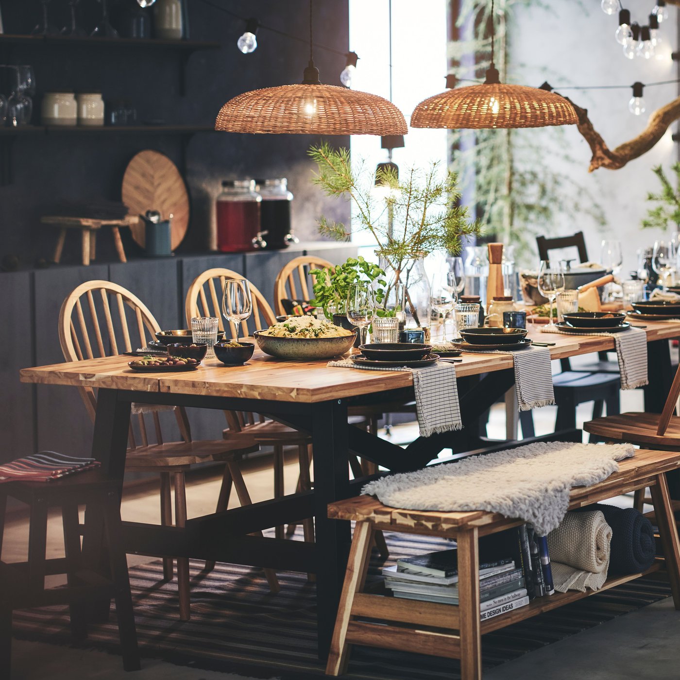 A SKOGSTA dining table with a black base and a wooden tabletop in the dining room, accompanied by wooden SKOGSTA dining chairs.