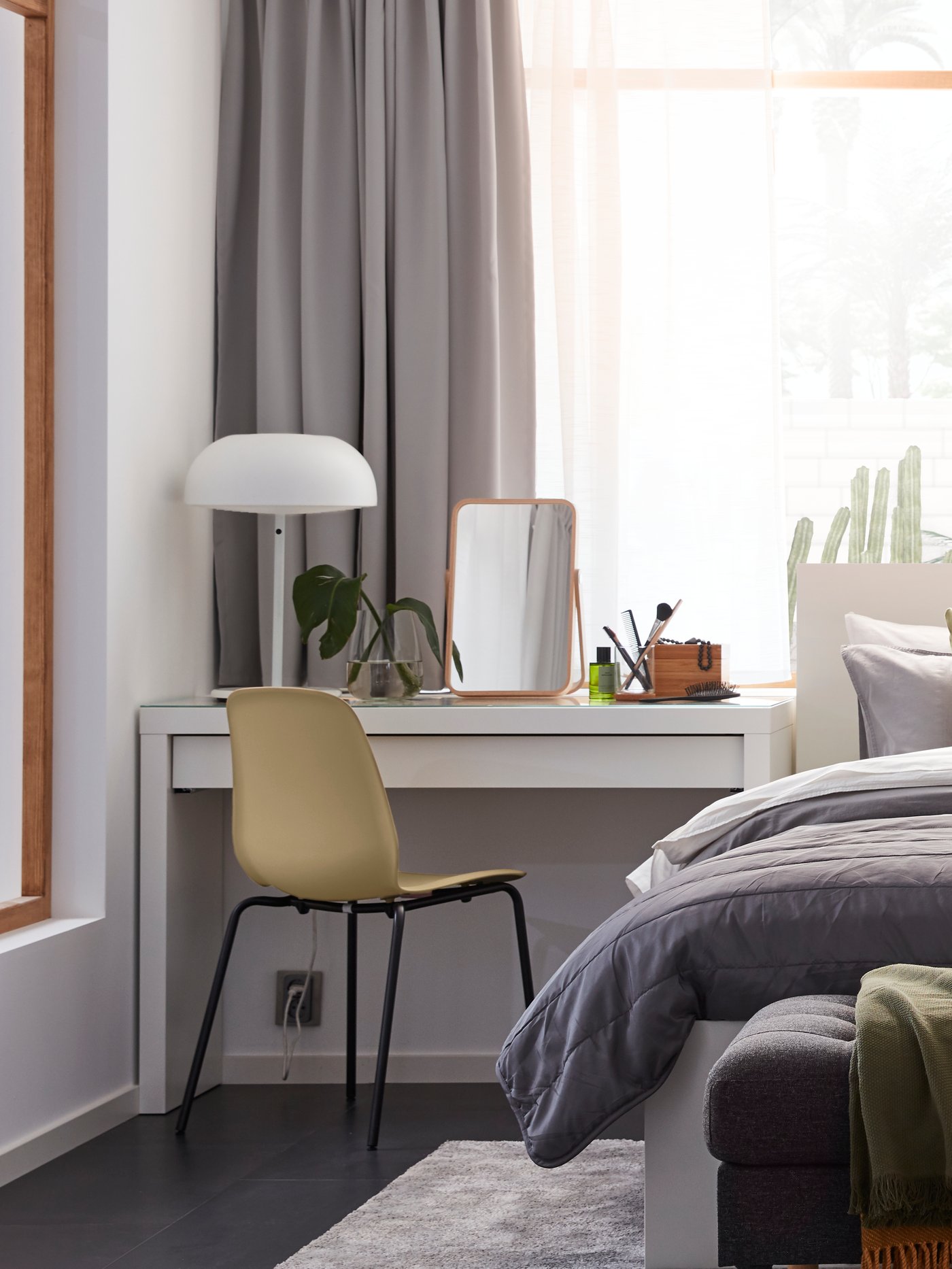 Un dormitorio con un tocador rectangular de madera y vidrio templado junto a una estructura de cama con 4 cajones de almacenaje.