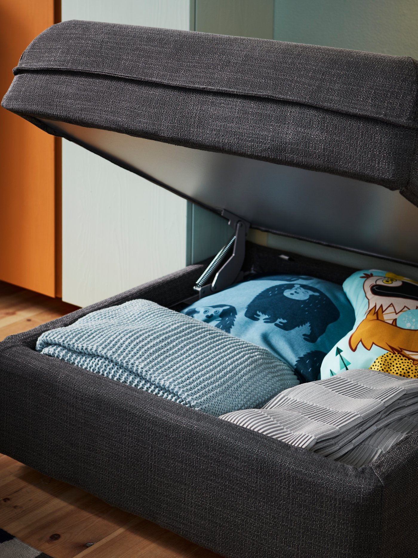 Otevřený modul pohovky VALLENTUNA odhalující uložené textilie a pléd.