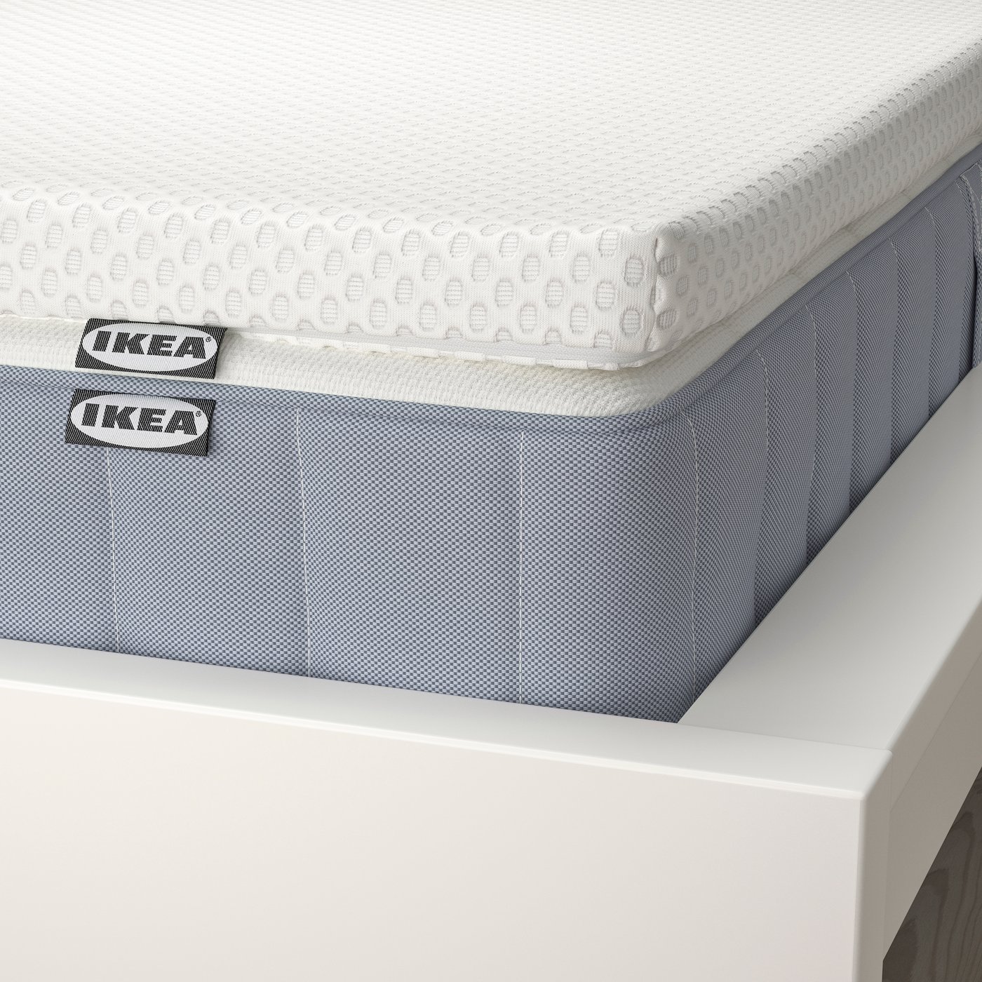 Eine feste VALEVÅG Matratze in Hellblau/Nordberget‑Weiss und eine Matratzenauflage.