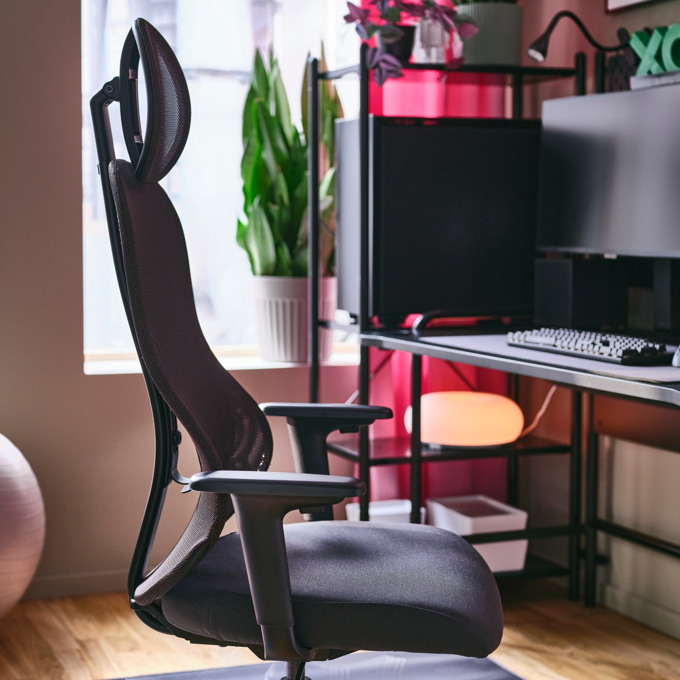 A home-gaming setup with a black UTKLASSNING gaming chair next to a black FRÖSKELÅS desk-and-shelving-unit combination.