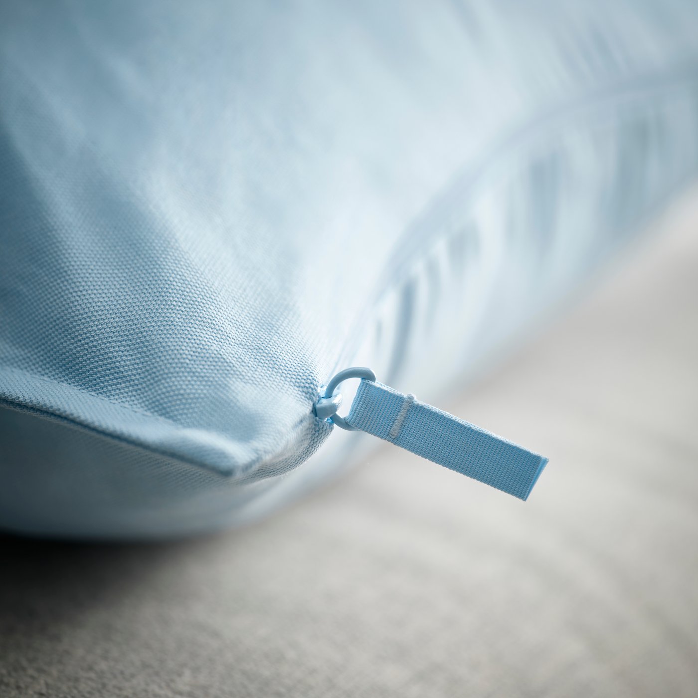 Gros plan sur une fermeture éclair bleue IKEA sur du tissu bleu clair, avec le curseur et la tirette bien visibles.