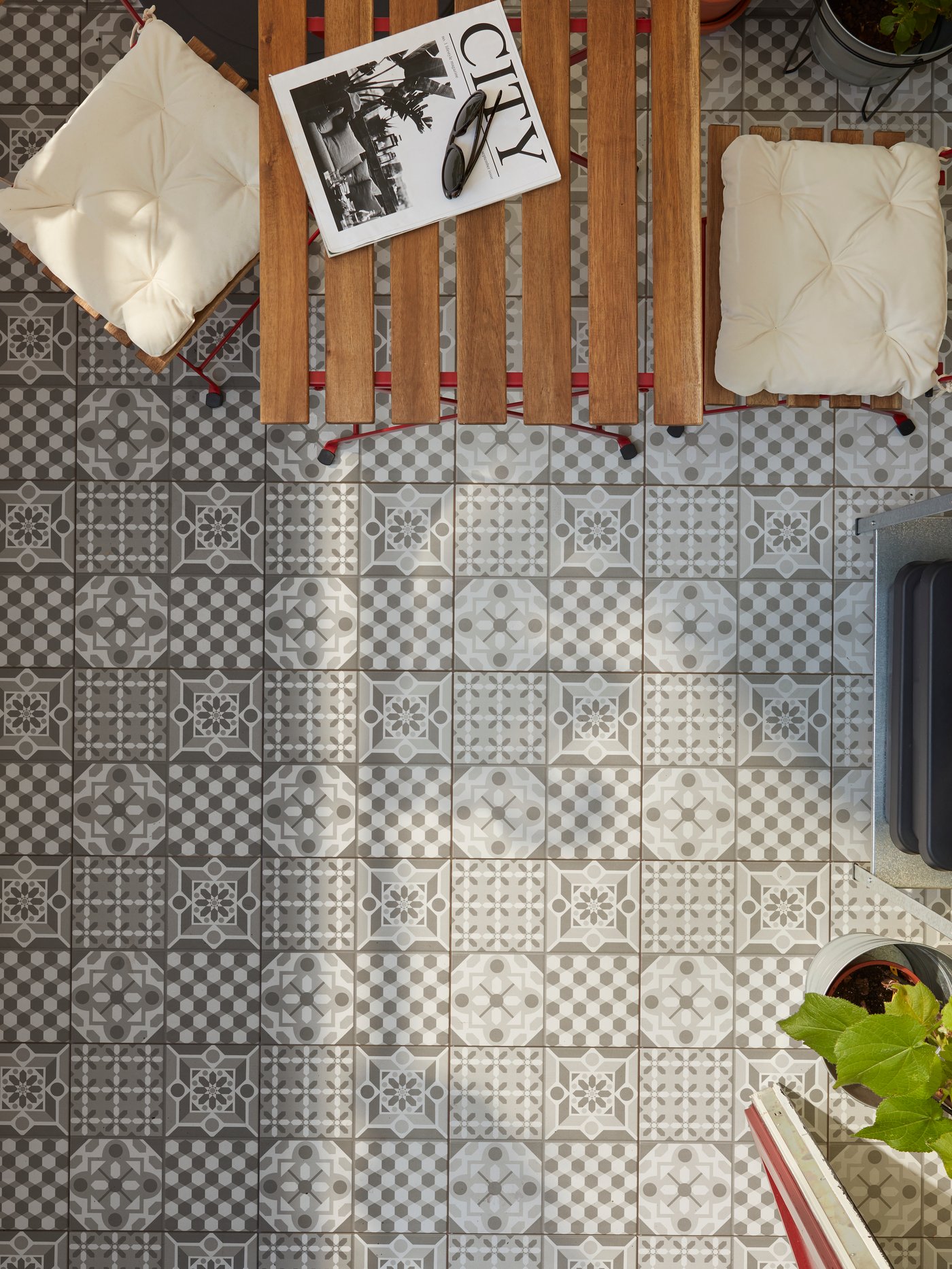 MÄLLSTEN floor decking with gray/white patterns, a table and chairs in red/light brown-stained wood and beige seating cushions.