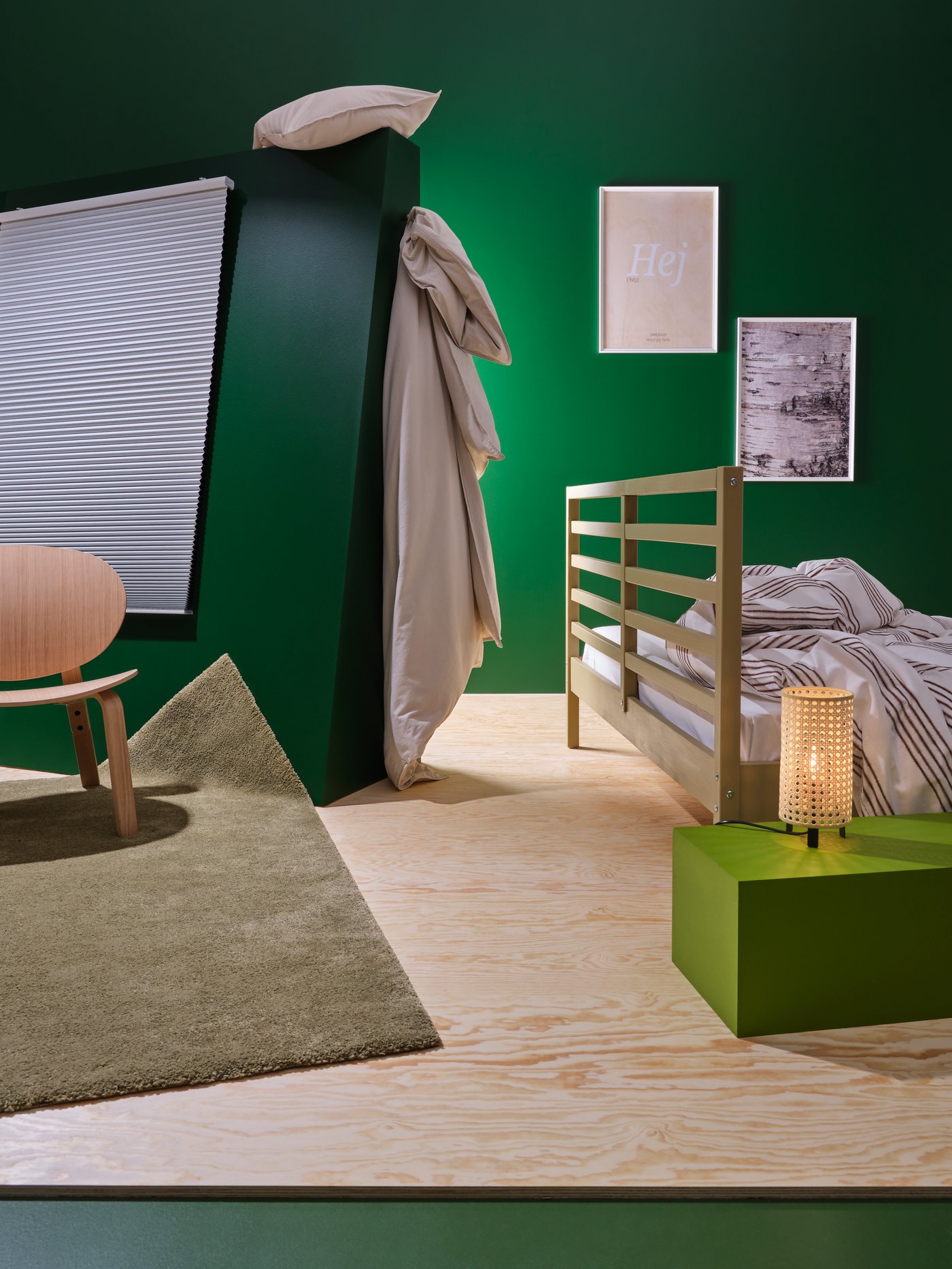 Dormitorio con una estructura de cama, un sillón, una alfombra de pelo corto, estores celulares opacos, marcos en la pared, una lámpara de mesa y ropa de cama.