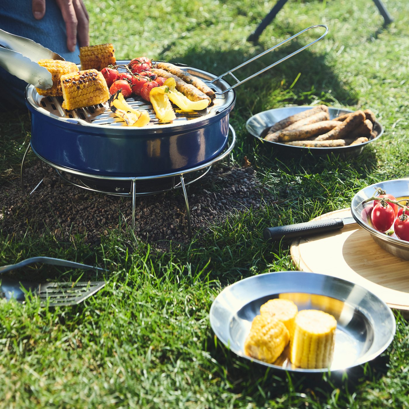 Grigliare le verdure al parco su un barbecue portatile STRANDÖN blu.