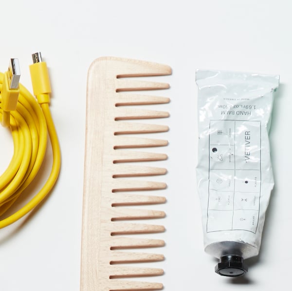 Part of a yellow charging cable, a hair comb, and a tube of hand cream. Part of a larger image of everyday items.