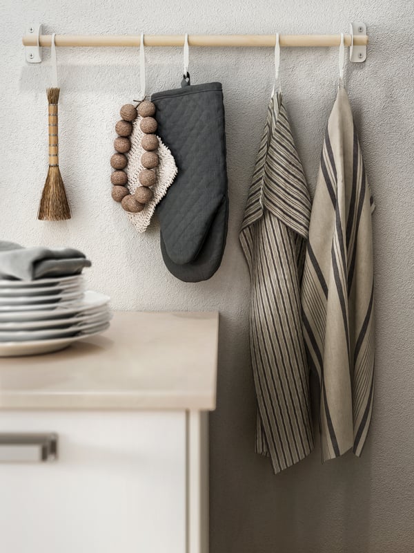Striped grey-beige MARIATHERES tea towels and a dark-grey oven glove hang from a NEREBY birch rail over a KASKER worktop.