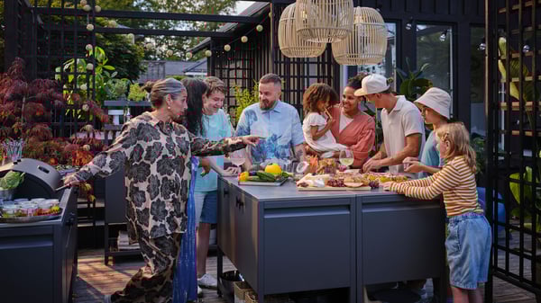 Amici e famiglia riuniti in una sera d’estate davanti a un barbecue su una terrazza.