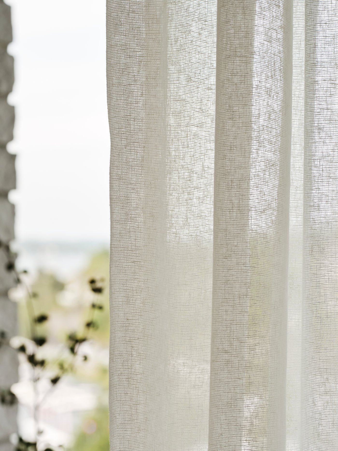En naturvit linnegardin i fönster. 