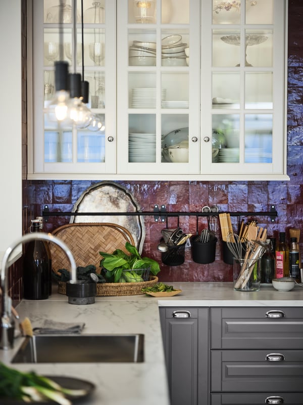 Una encimera con efecto de mármol blanco EKBACKEN con armarios METOD e interiores MAXIMERA en una cocina de azulejos rojos.