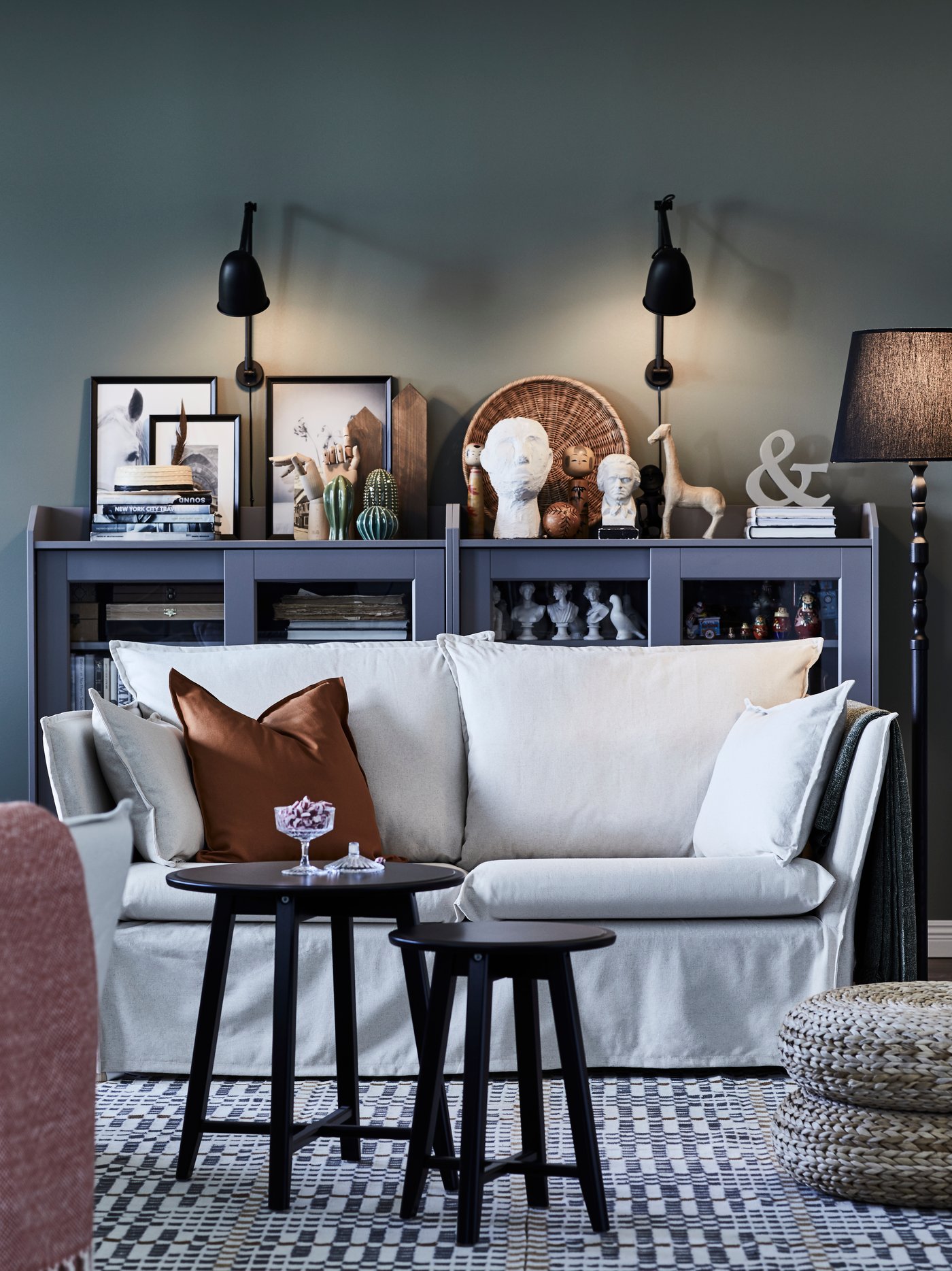 Ein Wohnzimmer im traditionellen Stil mit einem weißen 2 Sitzer Sofa, 2 Couchtischen und einer grauen Kommode im Hintergrund.