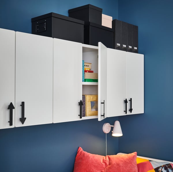 Praktische IKEA Wandregale mit weißen Schranktüren und schwarzen Aufbewahrungsboxen, ideal zur stilvollen und ordentlichen Organisation im Kinderzimmer