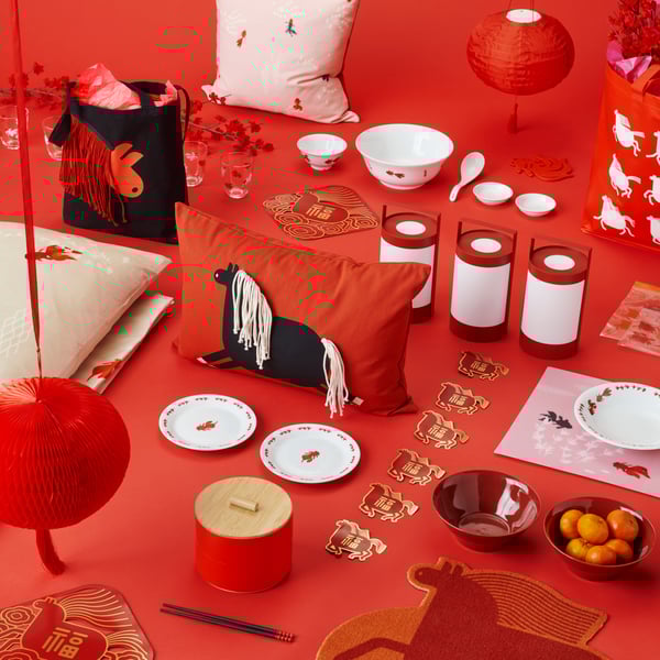 A decorative FÖSSTA cushion cover with a black horse design on a vibrant red background, surrounded by festive decor.