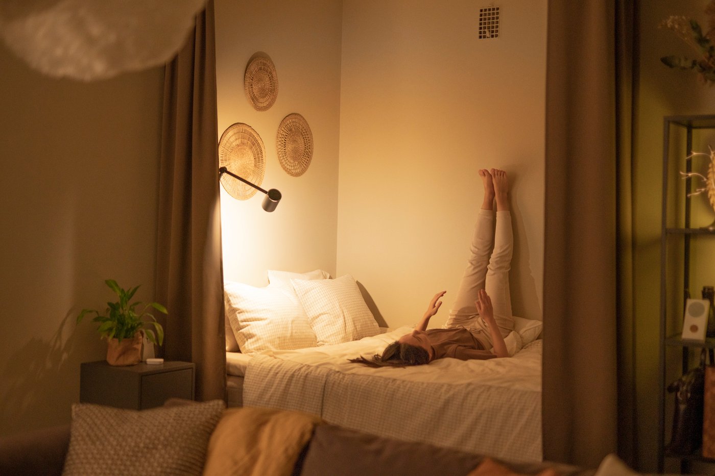 Woman stretching on the bed before bedtime, surrounded with warm yellow mood lights.