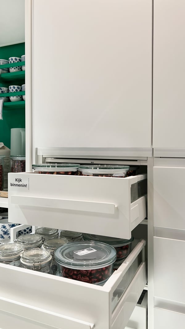 Open drawers in a white kitchen cabinet with VOXTORP fronts