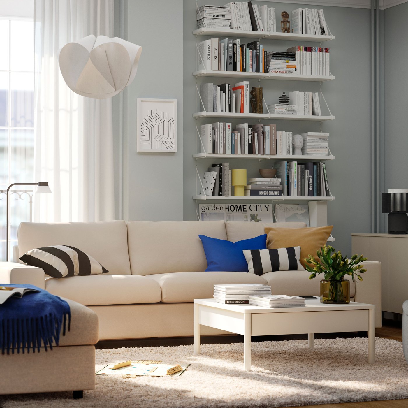 A beige VIMLE sofa and a white TONSTAD coffee table stand in front of the balcony doors in a sunny apartment.