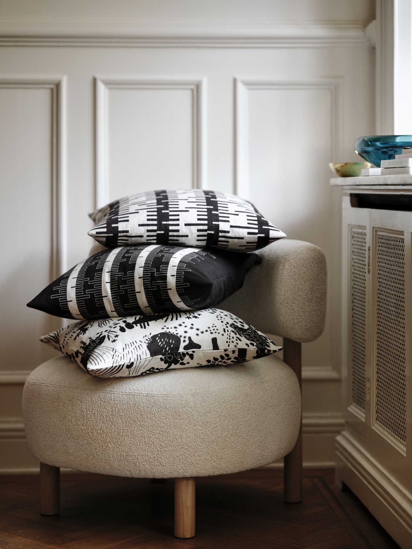 Jasnobeżowy fotel STOCKHOLM, na którym leżą trzy poduszki dekoracyjne z tej samej kolekcji.