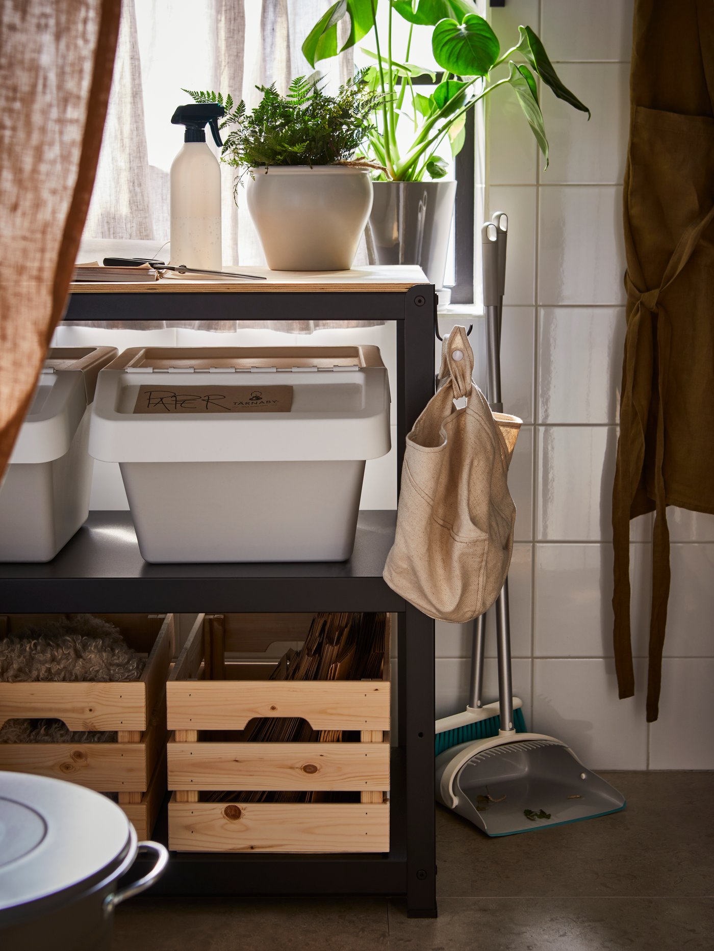 A BROR work bench with a plant in a pot on top and SORTERA waste sorting bins with lids and KNAGGLIG boxes on its shelves.