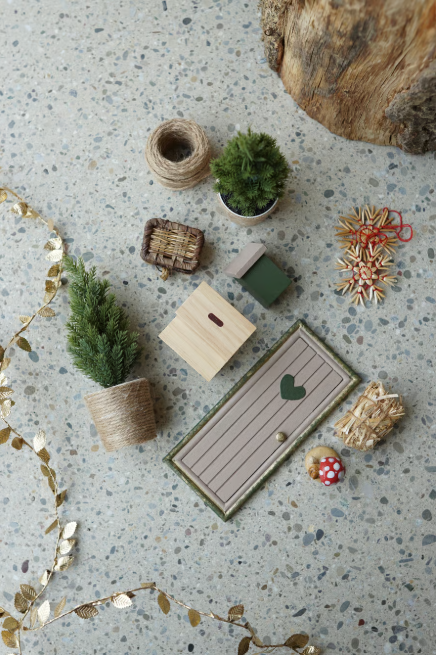 Wichteltür mit Herz, Mini-Weihnachtsbaum, Briefkasten, Pilzfigur und kleinen Accessoires auf hellem Boden dekorativ arrangiert. Festliche Adventsdekoration im skandinavischen Stil.