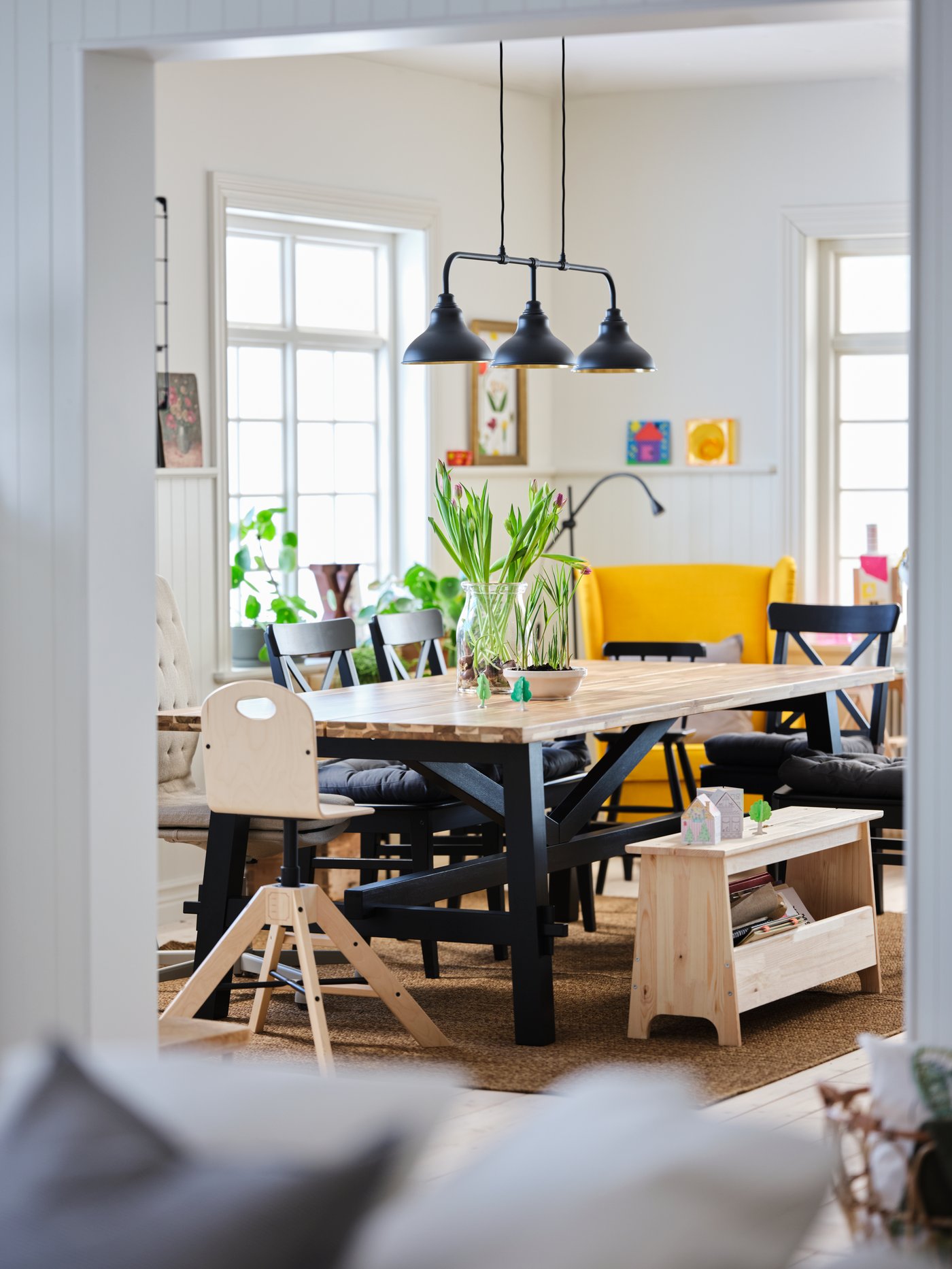 Living moderno con mesa de comedor rectangular de acacia maciza en el centro, junto a un banco beige con almacenaje.